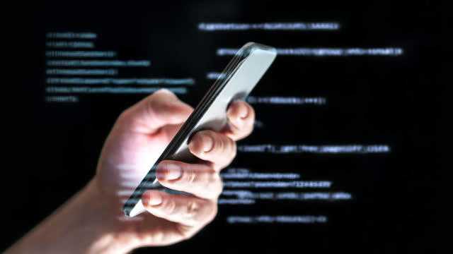 A hand holding a phone in front of lines of code